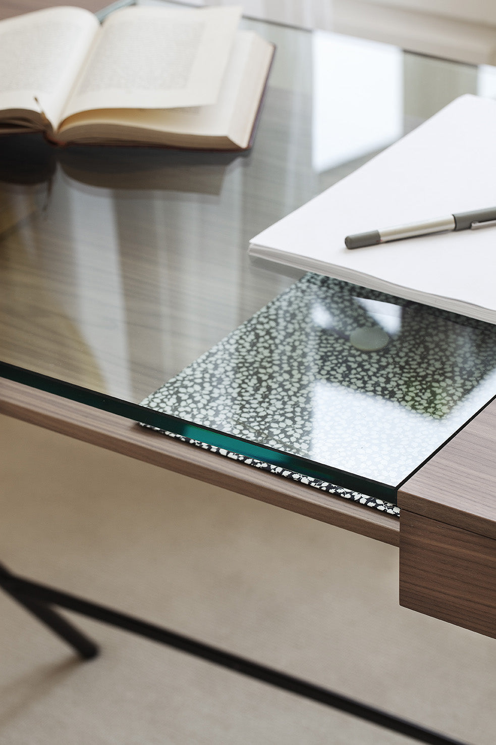 Livre et carnets rangés sur et sous le plateau en verre du bureau Cosimo verre et noyer canaletto