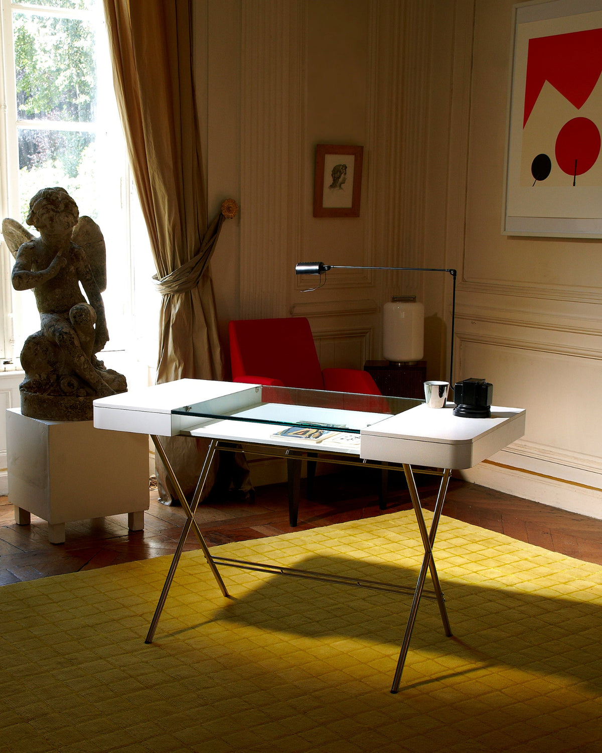 Bureau Cosimo verre et laqué blanc mat devant une sculpture et un tableau, intérieur classique